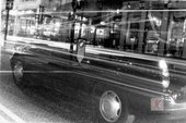 A photograph of a black cab on Oxford Street in black and white